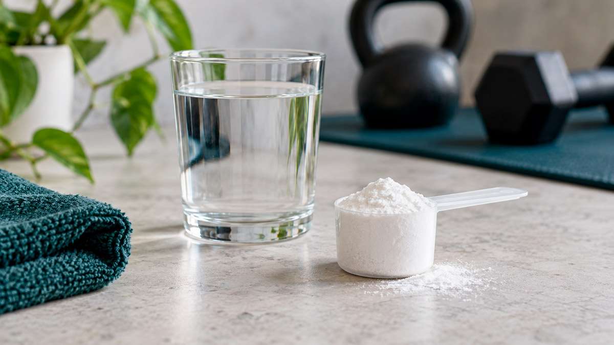 Creatina monohidrato en polvo junto a un vaso de agua